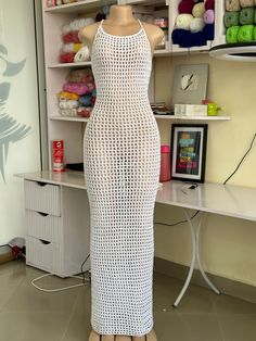 a mannequin wearing a white knitted dress in front of a sewing machine