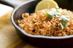 rice and cilantro in a skillet with lime wedges on the side