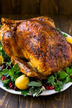 a roasted turkey on a platter with greens and lemons