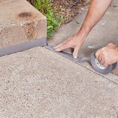 a man is using a tape to cut the concrete with a pair of scissors on it