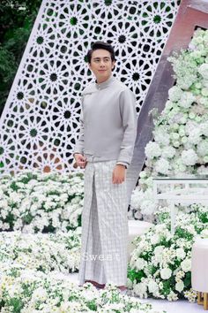 a man standing in front of a white flower garden with lots of flowers around him