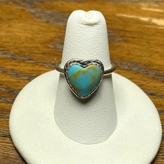 Authentic Turquoise Heart Silver Ring. Gorgeous And Unique Statement Piece. Sterling Silver Band (Unstamped), Turquoise With Natural Yellow/Brown Lining In A Heart Shape (925 Stamped), Sweet Braided Detailing Around The Heart, Scalloped Edging Around The Turquoise, The Stone Measures 10mm, And Made In Montana. Hard To Find Item! Size 6.5. Last Three Pictures Are The Actual Ring Being Sold. Handmade Blue Heart Shaped Ring, Handmade Blue Heart Ring, Heart-shaped Turquoise Ring, Bohemian Heart-shaped Anniversary Rings, Heart-shaped Turquoise Blue Ring For Gift, Heart-shaped Blue Turquoise Ring For Gift, Heart-shaped Blue Turquoise Ring Gift, Heart-shaped Turquoise Ring For Anniversary, Nickel Free Heart Shaped Ring