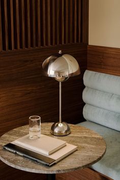 a table with a book and a glass on it next to a bed in a hotel room