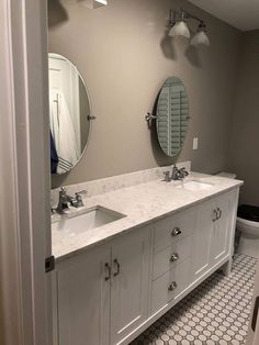 a bathroom with two sinks, mirrors and a toilet in the middle of the room