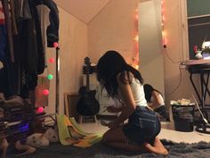 a young woman sitting on the floor in front of a mirror looking at her clothes