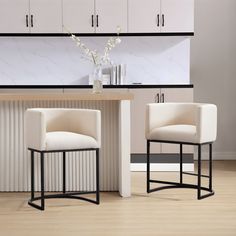 two white chairs sitting next to each other on top of a hard wood floor