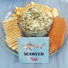 a glass plate with crackers, crackers and a bowl of food on it