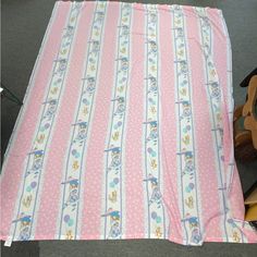 a pink and white striped blanket sitting on top of a wooden chair next to a teddy bear