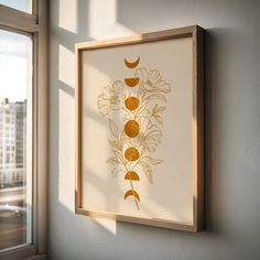 an art piece hanging on the wall next to a window with sunlight coming through it