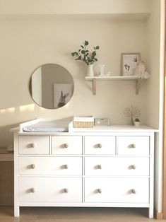 there is a white dresser with drawers and a mirror on the wall next to it