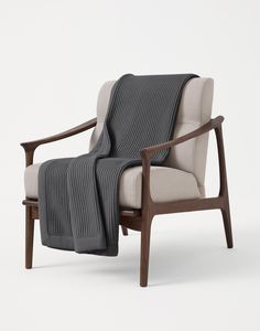 a chair with a blanket draped over it's back and arm rests on an upholstered wooden frame