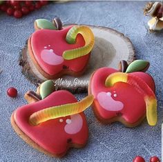 three decorated apple cookies sitting on top of a table