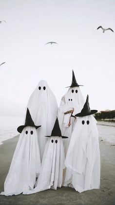 three white ghost figures are standing on the beach