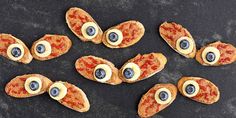 several pieces of pizza with googly eyes and blueberries in them on a black surface