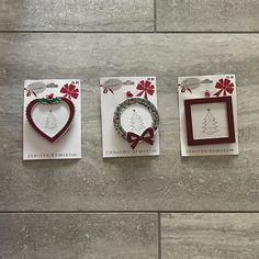 three cards with christmas designs on them sitting on a tile floor next to each other