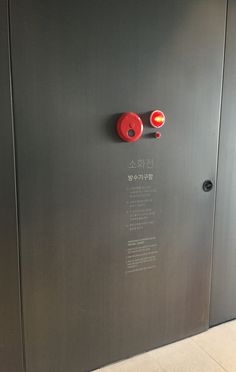 an elevator with two red knobs on the wall and one yellow button on the door