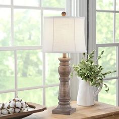 a wooden table with a lamp and some cotton balls on it in front of a window