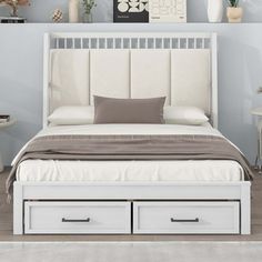 a white bed with two drawers underneath it and pictures on the wall behind it in a bedroom