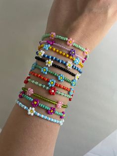 a woman's arm with several bracelets and beads on it, all in different colors