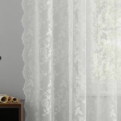 a window with white sheer curtains and flowers on it