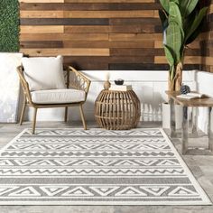 an outdoor area with two chairs and a rug on the floor next to a potted plant