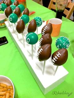 chocolate covered footballs and pretzels are on sticks in front of other snacks