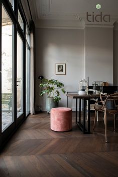 a living room filled with furniture and a table next to a large window covered in plants