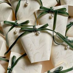 many white boxes with green ribbons and pearls on them are arranged together in the shape of hearts