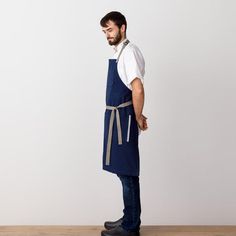 a man wearing an apron standing on a wooden floor