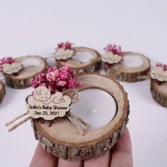 a hand holding a wooden slice with flowers on it and some tags attached to the wood