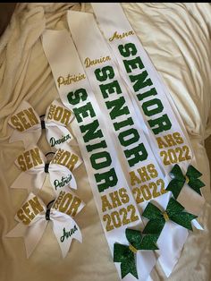 two white and green ribbons with the names of each team on them are laying on a bed