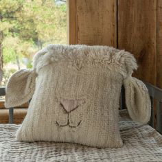 a sheep pillow sitting on top of a bed