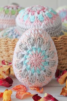 three crocheted eggs sitting on top of each other next to flowers and leaves