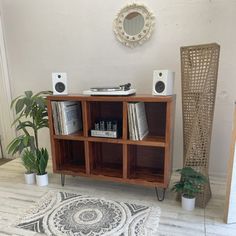 a living room with a rug, bookshelf and speakers on the sideboard