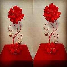 two vases with red flowers and candles on them