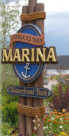 the sign for marina waterfront park is posted on a wooden pole in front of flowers