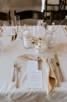 the table is set with silverware and flowers