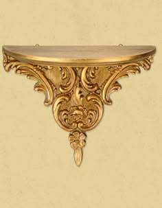 an ornate gold shelf on a beige wall with decorative carvings and scrolls around the edge