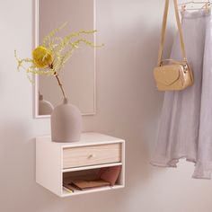 a white shelf with a mirror and vase on it next to a wall mounted coat rack