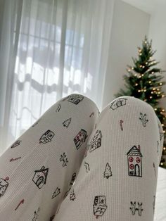 someone's feet in pajamas with christmas decorations on them and a small tree behind them