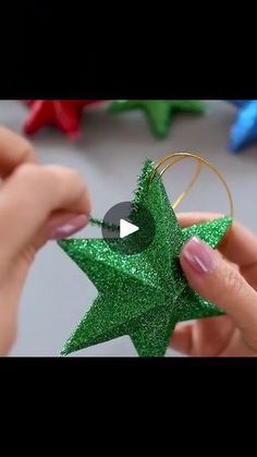 someone is making a star ornament out of glittery green paper and gold wire