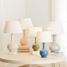 a table topped with lamps and books on top of a white table next to a window