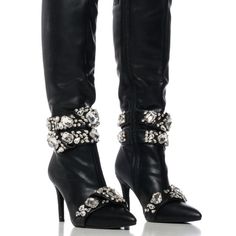 Edgy Elegance Starts With The Azalea Wang " Spotlight Takeover " Diamond Embellished Boot. This Glamorous Faux Leather Boot Features A Pointed Toe Silhouette, A Slim Stiletto Heel, A Knee-Height Shaft, And A Tonal Inner Ankle Zipper Closure. Complete With Silver Metallic Hardware, Chunky Rhinestone Gemstones, And Rhinestone Belted Accents Across The Calves And Toes. Style With A Midi Skirt And A Corset Top For A Romantic Look. - Faux Leather Upper - Pointed Toe - Stiletto Heel - 16.25 ” Shaft He Glamorous Embellished Evening Boots, Glamorous Evening Embellished Boots, Glamorous Embellished Boots For Night Out, Glamorous Embellished Fitted Boots, Glamorous Fitted Embellished Boots, Glamorous Embellished Party Boots, Chic Embellished Evening Boots, Glamorous Rhinestone Evening Boots, Pointed Toe Crystal Embellished Boots For Night Out