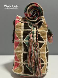 a small woven bag with tassels on the front and side, sitting on a white surface