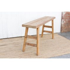 a wooden bench sitting on top of a rug next to a white wall and door