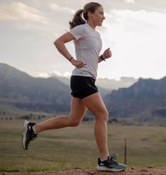 a woman running on a dirt road in the mountains