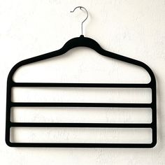 a black coat hanger hanging on a white wall