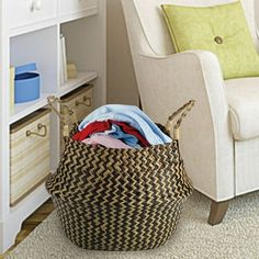 a basket filled with clothes sitting on top of a floor next to a white chair