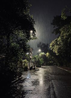 an empty street at night with the lights on and rain coming down from the sky