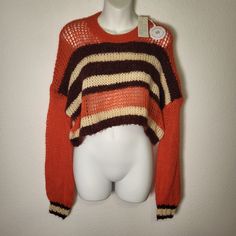 an orange and brown sweater hanging on a white mannequin